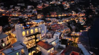 Geceleri Positano İtalya 'nın hava manzarası. Tepe boyunca uzanan şehir binaları ve oteller karanlık denize bakan parlak ışıklarla parıldıyor..