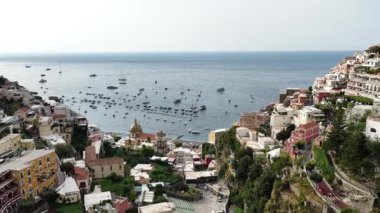 Positano İtalya 'nın muhteşem uçurum kenarındaki evleri açık mavi Akdeniz' e bakıyor. Birçok tekne güzel güneşli bir günde suları doldurur..