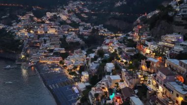 Hava perspektifi, Positano 'nun geceleri parladığını gösteriyor. Binaların ışıkları, yamaçtan sahile ve denize kadar suyla parıldıyor..