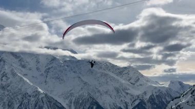 Chamonix Fransa 'nın karla kaplı dağlarının üzerinde bir paraglider uçuyor. Heyecan verici kış dağ macerasının tadını çıkar..