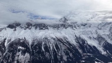 Kış panoraması Chamonix dağlarının kayan bulutların altında olduğunu gösteriyor. Kar örtüyor görkemli tepeler ve yamaçlar güzel bir dağ manzarası yaratıyor..