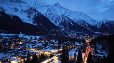 Fransa 'daki Chamonix Vadisi' nin panoramik manzarası. Karla kaplı dağlar aydınlatılmış köyü çevreleyecek kış gecesinde ışıklar parıldarken.