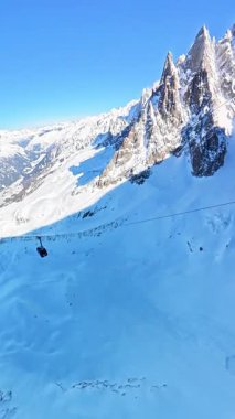 Parlak bir kış günü Chamonix yakınlarındaki Fransız Alpleri 'nin el değmemiş karlı zirvelerinde nefes kesici bir teleferik yolculuğu yaşayın..