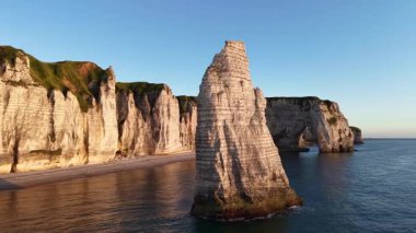Etretat Fransa 'nın ikonik beyaz tebeşir kayalıklarını ünlü Aiguille iğnesi kayaları ve altın ışıkla yıkanmış doğal kemer şekilleriyle deneyin..