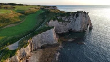 Görkemli tebeşir kayalıklarını, doğal kemerleri ve Aiguille kaya oluşumunu Normandiya 'nın Etretat kıyısında altın ışıkla yıkanan.