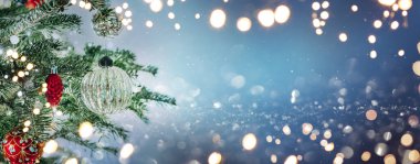 Kırmızı ve gümüş süslemeli Noel ağacı mavi arka planda bokeh ile parıldıyor. Mutlu Noeller ve mutlu yıllar tebrik kartı. Xmas ve kış tatili. Noel bayrağı