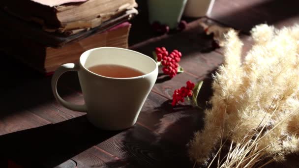 Белая Чашка Чая Деревянном Столе Старые Книги Листья Красные Ягоды — стоковое видео