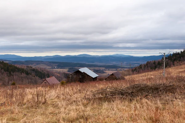 Mountain Valley Landscape With Dry Golden Grass And Rustic Wooden Cabins Under Cloudy Sky In Calm Countryside