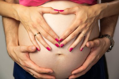 Çift Kollu Hamile Karnı Sembolü. Doğum Sevgisi ve Aile Bebek Bekliyor