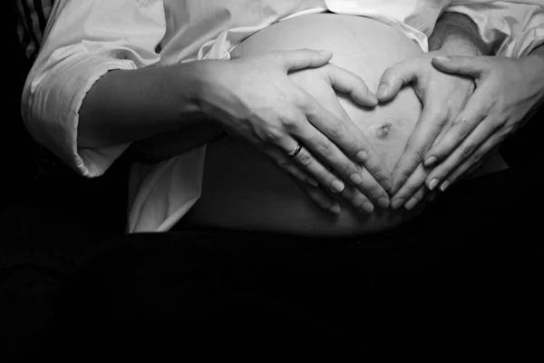 Pregnancy Belly With Couple Hands Heart Symbol Showing Love Maternity Expecting Family Parents. Intimate Black And White Maternity Photoshoot
