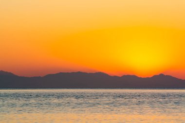 Dağ Silueti ile Deniz Üzerindeki Altın Gün Batımı Sakin Akşam Dramatik Sıcak Gökyüzü Manzarası