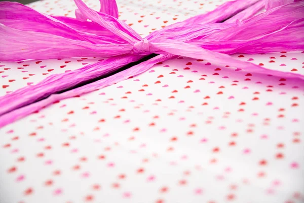 Large Gift Wrapped In Heart Pattern Paper With Bright Pink Ribbon. Wedding Celebration Present Detail Close-Up