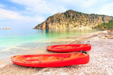Masmavi denizin taş kıyısında iki kano 