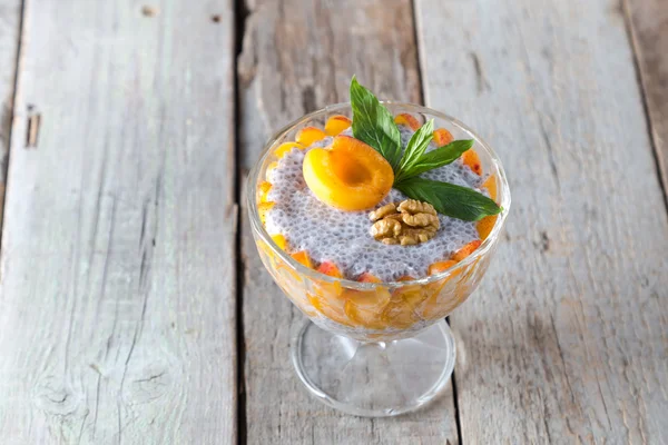 Raw vegan dessert: Chia seeds pudding with apricots and mint on a wooden background.