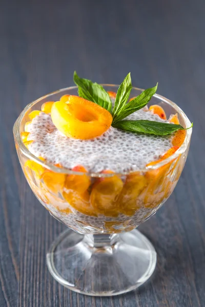 Raw vegan dessert: Chia seeds pudding with apricots and mint on a dark wooden background.