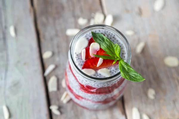 Raw vegan dessert: Chia seeds pudding with strawberries on a wooden background