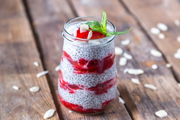 Raw vegan dessert: Chia seeds pudding with strawberries on a wooden background