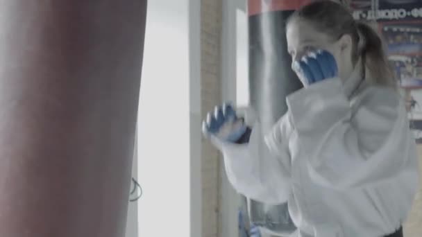 Taekwondo chica trenes con saco de boxeo en el gimnasio — Vídeos de Stock