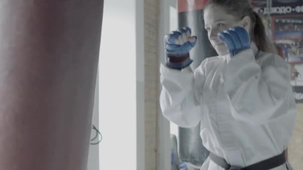 Slowmotion Taekwondo flicka tåg med slagsäck i gymmet — Stockvideo