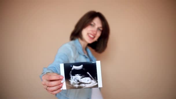 Schwangere Zeigt Ultraschallbild Während Sie Bauch Auf Gelb Berührt — Stockvideo