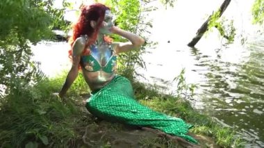 Mermaid sits on the shore around the water slow motion
