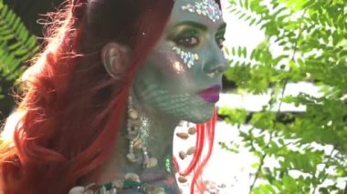 Mermaid with red hair near the water in the trees slow motion
