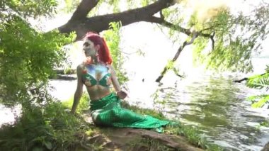 Deniz kızı kıyıda oturur suyun etrafında ağır çekimde