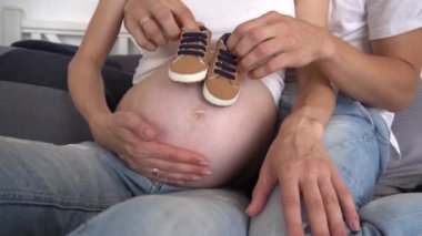 Slow Motion Man, kadın göbeğine bebek ayakkabıları koyuyor. 
