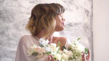 Beyaz güller içindeki gelinin sabahı elinde bir düğün buketi tutuyor.