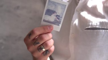 Eller fotoğraf çeker. Polaroid bir resim geliştir. Beyaz kart ellerinde..