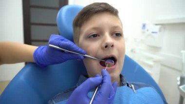 4K Dişçi klinikte küçük çocuğun dişlerini inceliyor.