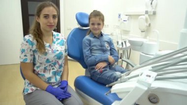 Yavaş çekim gülümseyen küçük kız dişçiye beş dolar veriyor, dişçi koltuğuna.