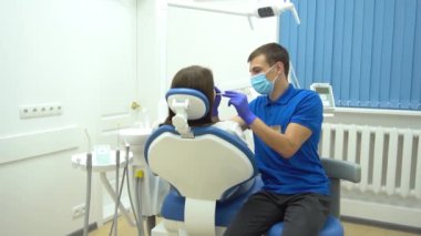 Avrupalı genç bir kadın dişçide dişlerini düzeltirken sağlık koltuğunda oturuyor. 