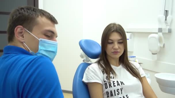 当牙医试图治疗她的牙齿时 吓坏了的年轻妇女眯着眼 用手捂住嘴 — 图库视频影像