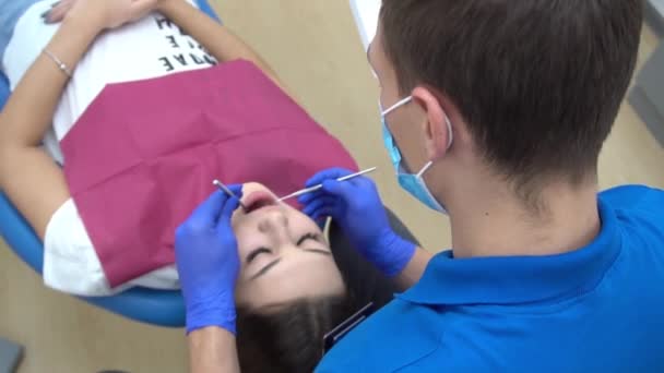 年轻英俊牙医检查坐在牙医上的快乐女性病人的牙齿 — 图库视频影像