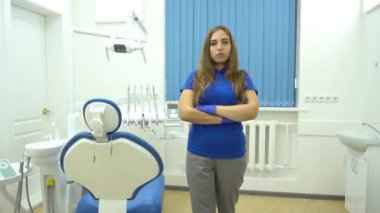 Önlüklü gülümseyen kadın dişçinin portresi. Clini 'de kolları çaprazlanmış duruyor.