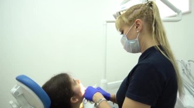 Slow Motion Avrupalı orta dişçi yüz maskeli kadın diş kliniğinde çalışıyor.
