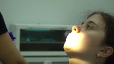 Güzel bir kadın hasta dişçi muayenehanesinde diş tedavisi görüyor. Kadın ziyareti