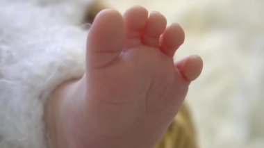 Yeni doğan bebeğin ayakları örülmüş beyaz bir battaniyeye sarılıdır. Yeni doğan bebek...