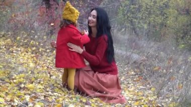 Mutlu aile annesi ve kızı sonbahar parkında oynar ve güler.