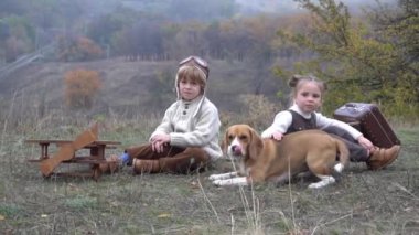 Sonbahar parkında köpeği olan çocuklar Jack Russell Terrier oynuyor.