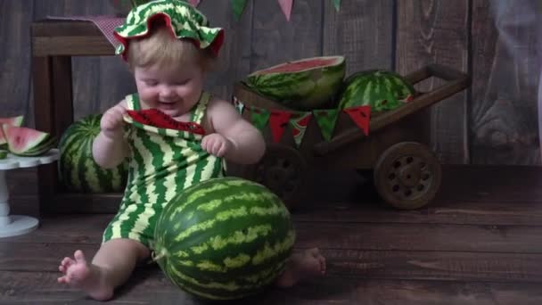 Girl Green Romper Wooden Background Looking Watermelon — Stockvideo