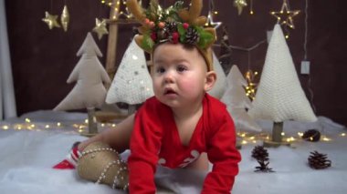 Noel kostümlü şirin bir bebek ve evde yerde Noel süslemeleri..