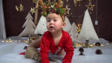 Yavaş Hareketli kostüm giyen çocuk, arka planda geyik boynuzlarıyla oturuyor.