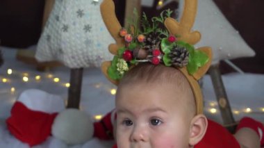 Küçük bir bebek Noel geyiği boynuzu takıyor. Noel ve Yeni Yıl