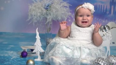 Yavaş hareket eden mavi gözlü bebek, Noel ağacının yanında yatıyor.
