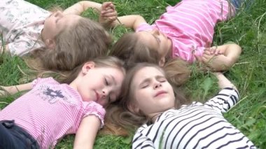 Slow Motion Happy çocukları çimlerin üzerinde yatıyor. Parkta oynayan komik çocuklar. Üst görünüm