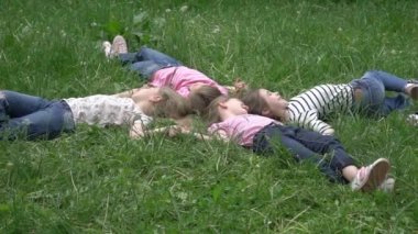 Yavaş hareket eden neşeli arkadaşlar çimenlere uzanıp gülerler.