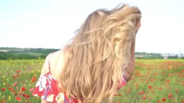 Slow Motion. Elbise ve şapka giymiş güzel genç kız çiçek tarlasında yürüyor.