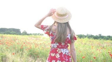 Slow Motion. Elbise ve şapka giymiş güzel genç kız çiçek tarlasında yürüyor.
